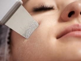 Donna con gli occhi chiusi riceve trattamento viso con spatola ultrasonica.